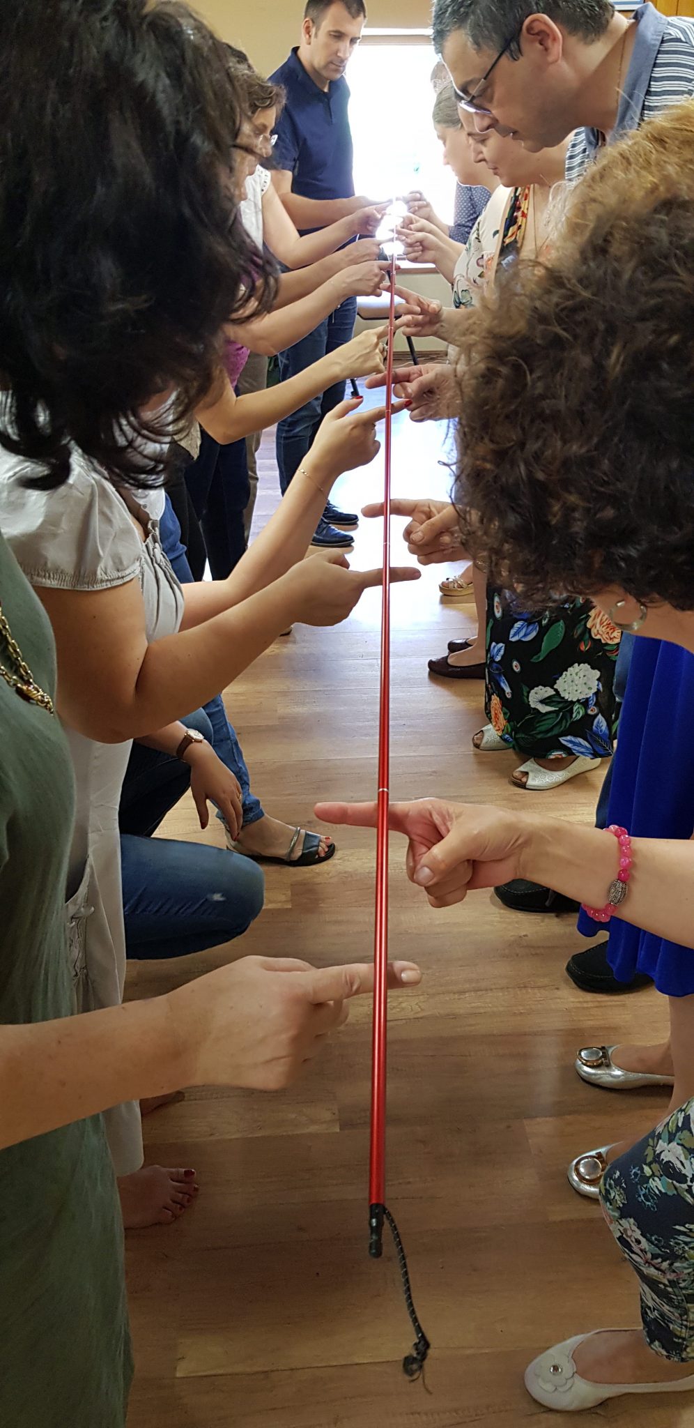 Participanți la team building care țin împreună o sfoară roșie într-un exercițiu de coordonare